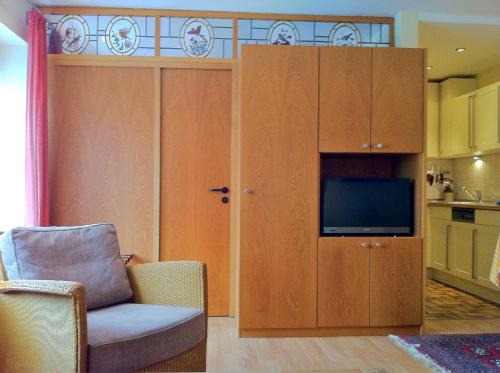 ein Wohnzimmer mit einem TV, einem Stuhl und einem Schrank in der Unterkunft Ferienwohnung Familie Böckmann auf Norderney in Norderney