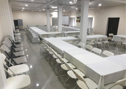 a room with white tables and chairs and a screen at Hotel Cabenda in Freetown