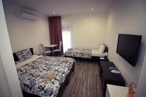 a hotel room with two beds and a television at Apartments & Rooms Villa Zaad FREE PRIVATE PARKING in Mostar