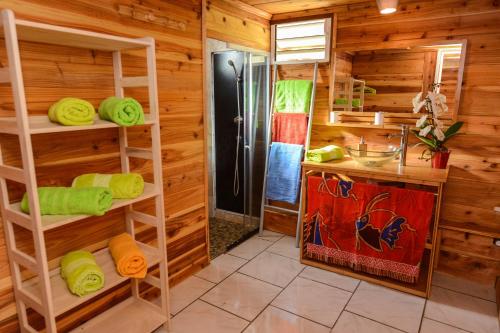 a bathroom with wooden walls and a shower and towels at Le Chalet à Joel in Cilaos
