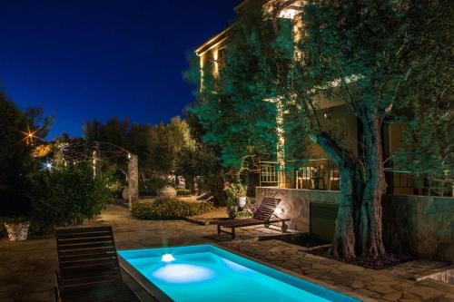 a swimming pool in front of a house at night at Ampoulos Rooms & Apartments in Kedro