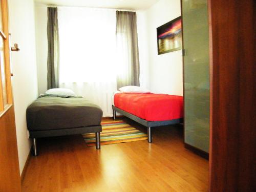 ポズナンにあるBukowska Apartmentのベッド2台と窓が備わる小さな客室です。