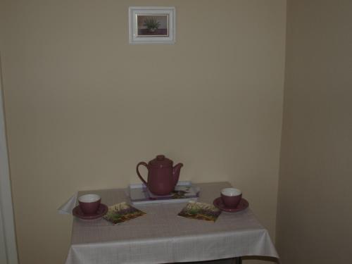 a table with a tea pot and two cups on it at Levendula Apartman in Szekszárd