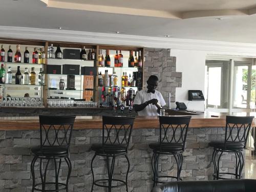 a man standing at a bar in a restaurant at Hotel Cabenda in Freetown