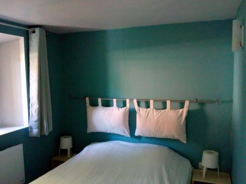 a bedroom with a green wall with a bed with pillows at 7 Rue du Docteur Paul Jouve in Digne-les-Bains