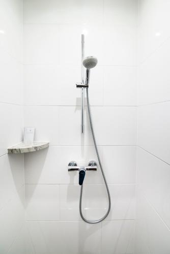 a shower in a white bathroom with a hose at Pod Ksiecia Gorka in Oleszyce