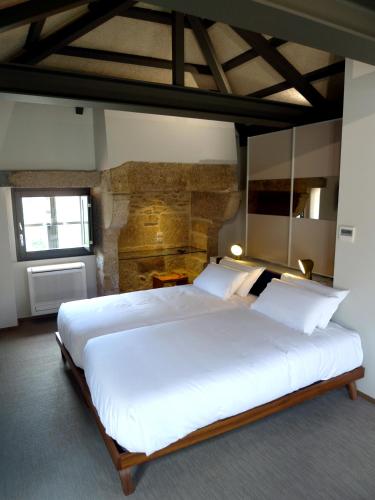a bedroom with a large bed with white sheets and pillows at Blanco Apartamentos Turísticos in Santiago de Compostela