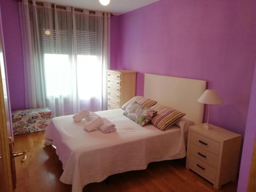 Un dormitorio con paredes moradas y una cama con toallas. en Calle Maceiras, 1 - 1B, en Combarro