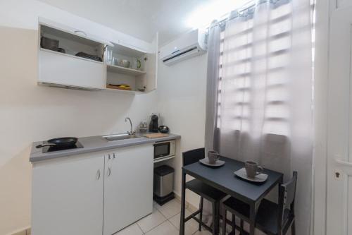 a small kitchen with a small table and a sink at Locastudio - Carambole in Sainte-Anne