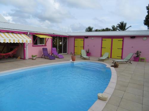 a swimming pool in front of a pink and yellow house at Gite KAZ A LILINE in Le Moule