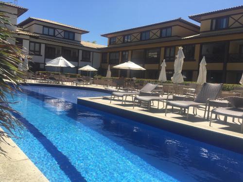 un resort con piscina attrezzata con sedie e ombrelloni di Apartamento 01 Enseada Praia do Forte a Praia do Forte