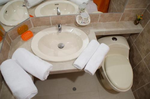 a bathroom with a sink and a toilet with towels at Jazmines Lodging in Ica