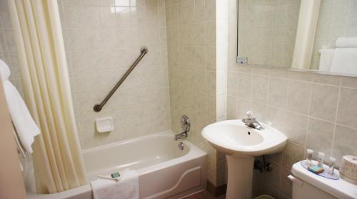 a bathroom with a sink and a tub and a toilet at Travelodge by Wyndham Niagara Falls At the Falls in Niagara Falls