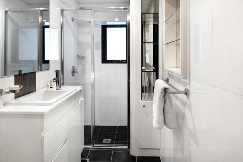 a white bathroom with a shower and a sink at Veriu Randwick in Sydney