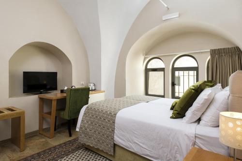 a bedroom with a bed and a desk with a television at The Sephardic House Hotel in The Jewish Quarter in Jerusalem