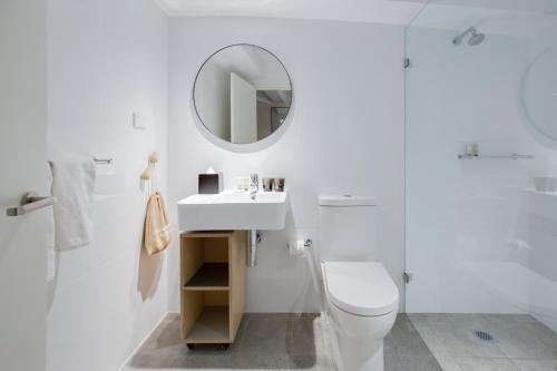 a white bathroom with a toilet and a mirror at Veriu Broadway in Sydney