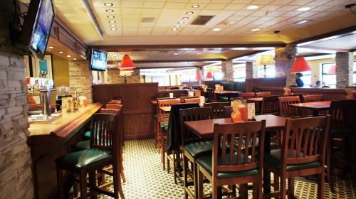 a restaurant with wooden tables and chairs and a bar at Travelodge by Wyndham Niagara Falls At the Falls in Niagara Falls