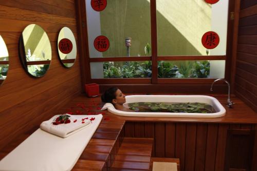 uma mulher está numa banheira num quarto em Mabu Thermas Grand Resort em Foz do Iguaçu