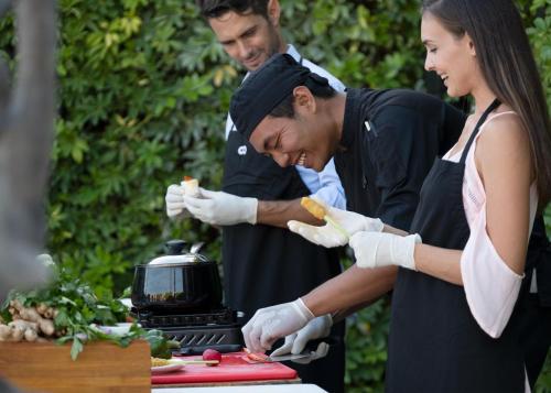 a group of three people preparing food on a grill at eqUILIBRIA Seminyak in Seminyak