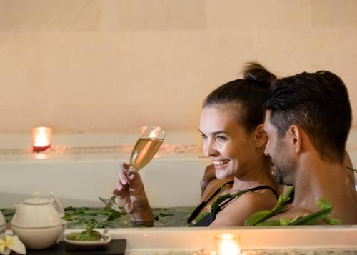 a man and woman in a bathtub looking at a mirror at eqUILIBRIA Seminyak in Seminyak