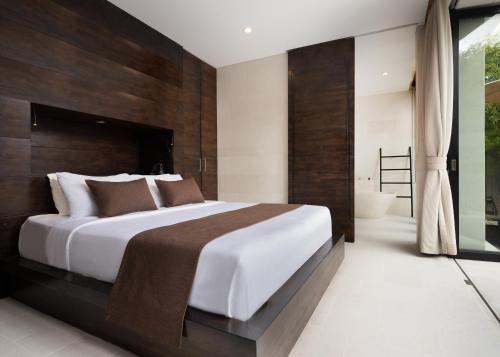a bedroom with a large bed and a bathroom at eqUILIBRIA Seminyak in Seminyak