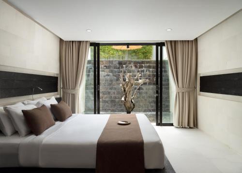 a bedroom with a large bed and a large window at eqUILIBRIA Seminyak - CHSE Certified in Seminyak