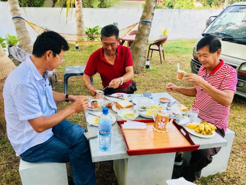 three men sitting at a table eating food at White Villa Airport Transit Hotel in Katunayake