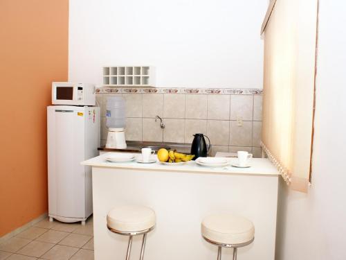 a kitchen with a counter with stools and a refrigerator at Hotel - Apart-hotel Chalé Executivo in Mossoró