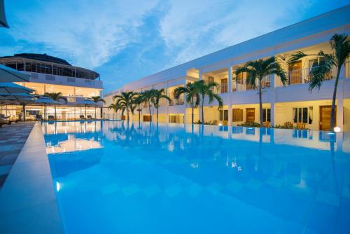 a large swimming pool in front of a building with palm trees at Palma Resort Phu Quoc, Trademark Collection by Wyndham in Phú Quốc