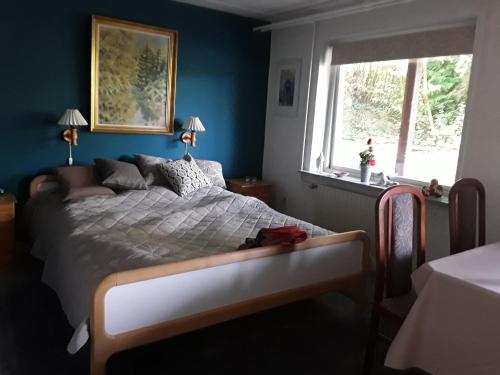 a bedroom with a bed with a blue wall at Kjellerup bed&Breakfast in Kjellerup