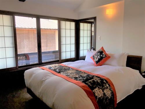 a bedroom with a large bed with two windows at Kamishichiken Oku in Kyoto