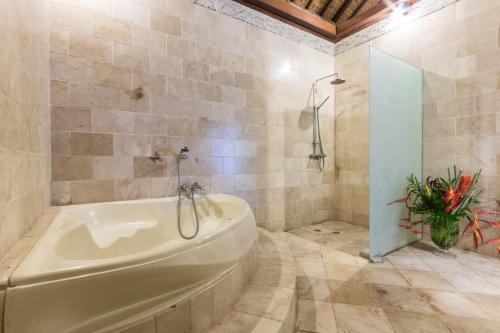 a bathroom with a tub and a plant in it at Casa Jimbaran Villa in Jimbaran