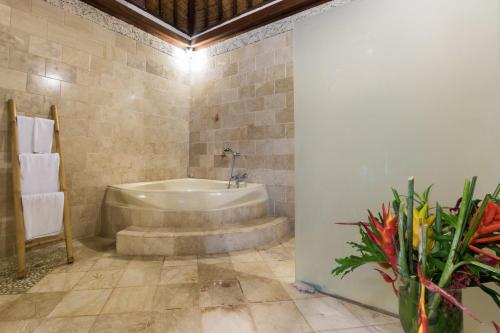 a bathroom with a tub and a vase of flowers at Casa Jimbaran Villa in Jimbaran