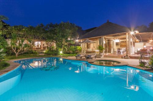 a swimming pool in front of a house at night at Casa Jimbaran Villa in Jimbaran