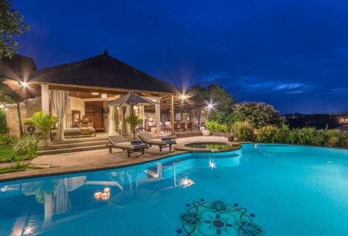 a swimming pool in front of a house at night at Casa Jimbaran Villa in Jimbaran