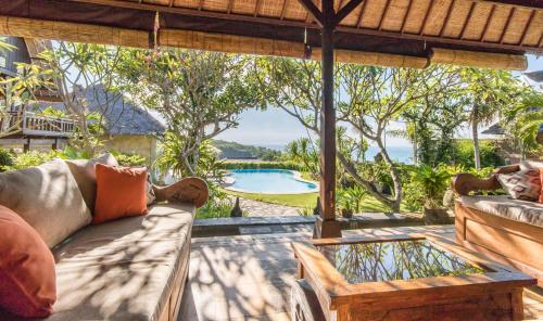 a patio with a couch and a table and a pool at Casa Jimbaran Villa in Jimbaran