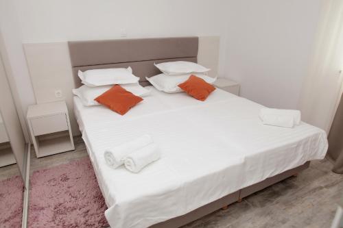Una cama blanca con almohadas naranjas y blancas. en Villa Marija en Slatine