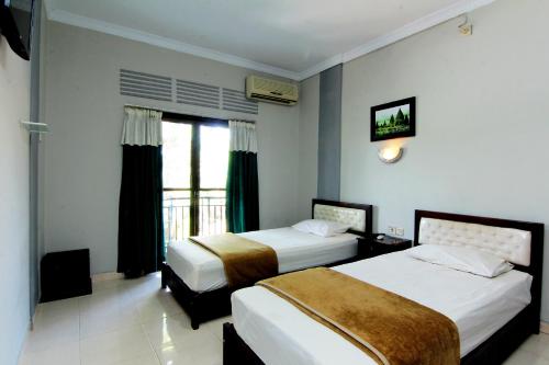 a hotel room with two beds and a balcony at Hotel Bugis Asri in Yogyakarta
