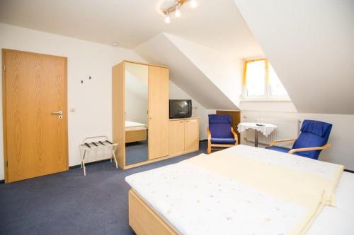 a bedroom with a bed and two blue chairs at Hotel Pizzeria VENEZIA in Sohren