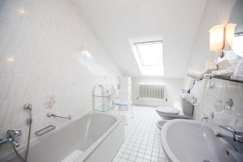 La salle de bains blanche est pourvue d'une baignoire et de 2 toilettes. dans l'établissement Hotel Pizzeria VENEZIA, à Sohren