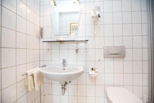 a white bathroom with a sink and a toilet at Hotel Pizzeria VENEZIA in Sohren