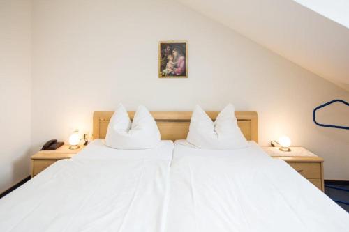 two beds in a room with white sheets at Hotel Pizzeria VENEZIA in Sohren