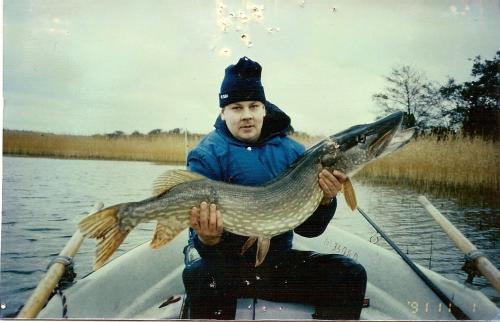 a man in a boat with a fish in his hand at Söderö Stugby in Finström