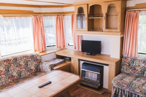 uma sala de estar com televisão e lareira numa caravana em Domki nad jeziorem Mieruniszki em Filipów