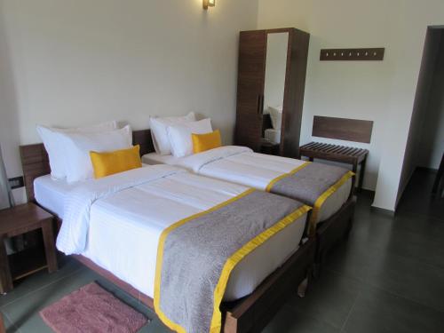 a bedroom with two beds with yellow and white pillows at Falcon Crest in Vagamon