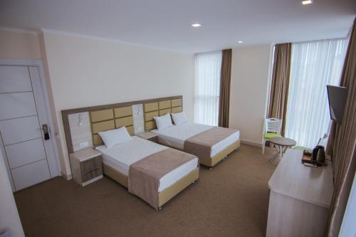 a hotel room with two beds and a television at Hotel Green Glass in Batumi