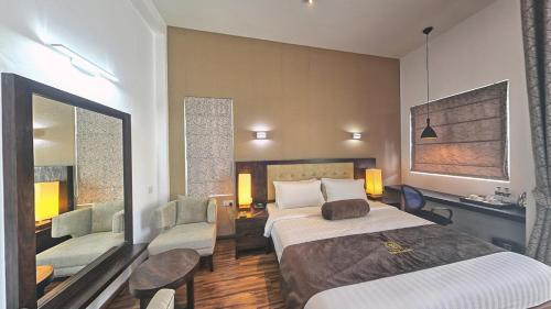 a hotel room with a bed and two chairs at Ripon Grand Hill By EHI in Nuwara Eliya