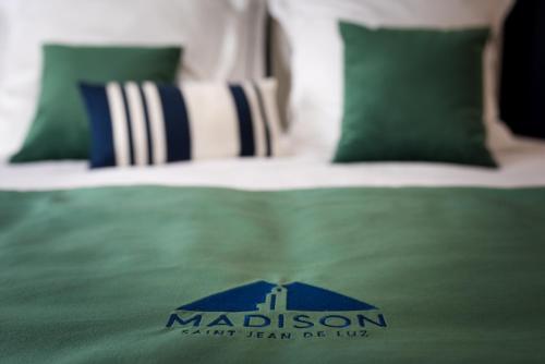 a bed with a green comforter with a malcolm sqor at MADISON Saint Jean de Luz - Handwritten Collection in Saint-Jean-de-Luz