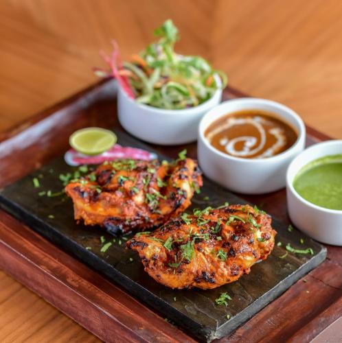 a plate of food with chicken wings and dipping sauces at Lemon Tree Premier “The Atrium” Ahmedabad in Ahmedabad