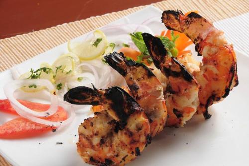 a plate of food with shrimp and vegetables on a table at Lemon Tree Premier “The Atrium” Ahmedabad in Ahmedabad